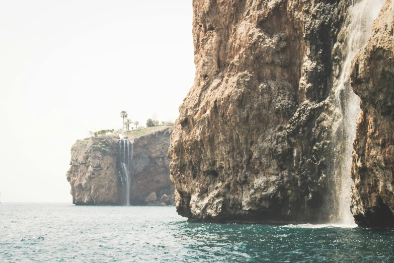 a waterfall in the middle of a large body of water, pexels contest winner, les nabis, in socotra island, photo taken from a boat, cliff edge, high quality product image”