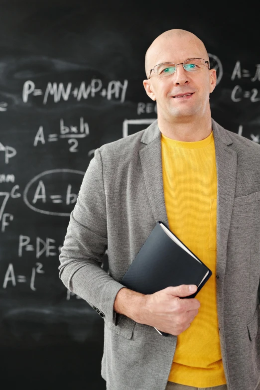 a man standing in front of a blackboard holding a book