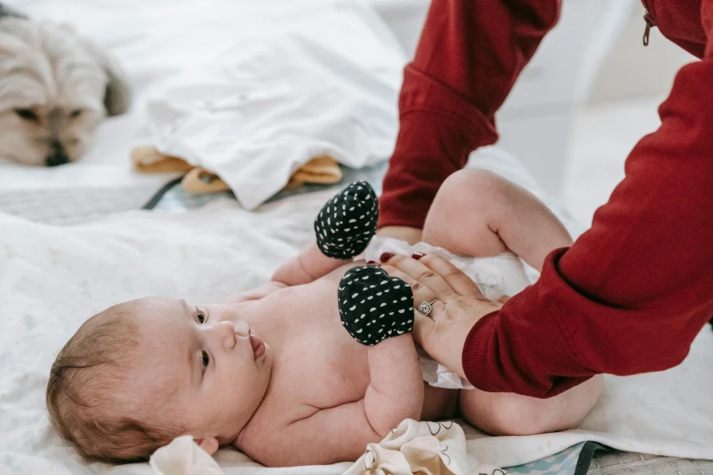 a close up of a baby laying on a bed, by Nina Hamnett, pexels contest winner, incoherents, bandage on arms, mittens, palm body, gif