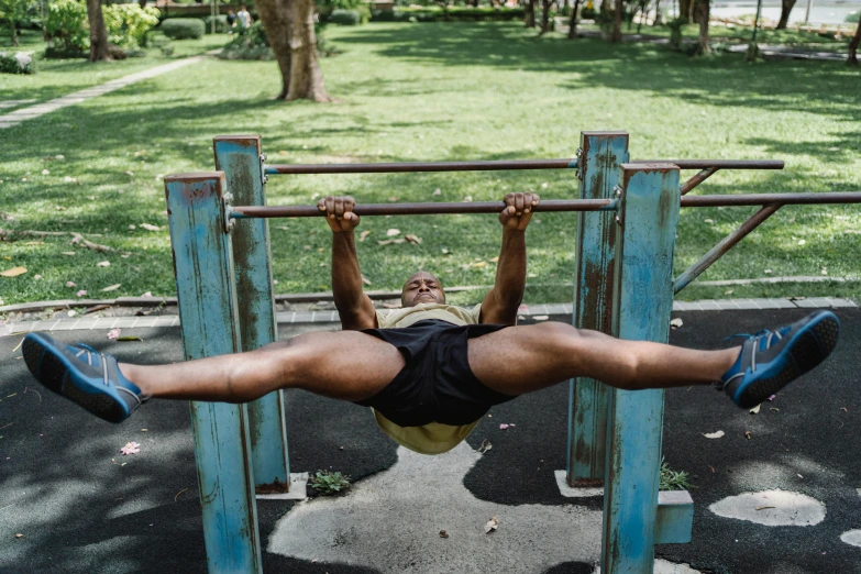 a man on a monkey bar in a park, pexels contest winner, laying on the ground, local gym, sri lanka, vascularity