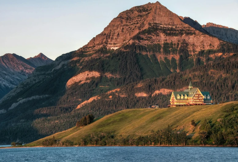 a large building sitting on top of a lush green hillside, banff national park, mountains and oceans, pink golden hour, promo image