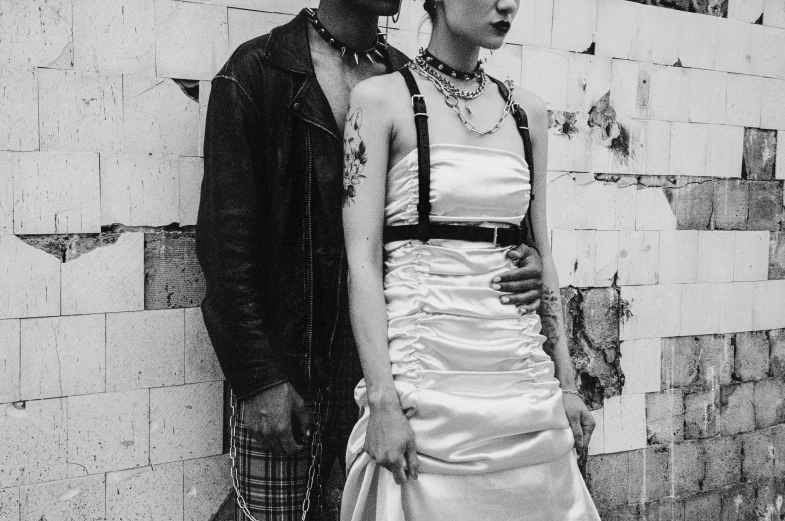 a man and a woman standing next to each other, a black and white photo, by Lucia Peka, pexels, renaissance, wearing punk clothing, apocalypse wedding, wearing chains, as fashion editorial 90s