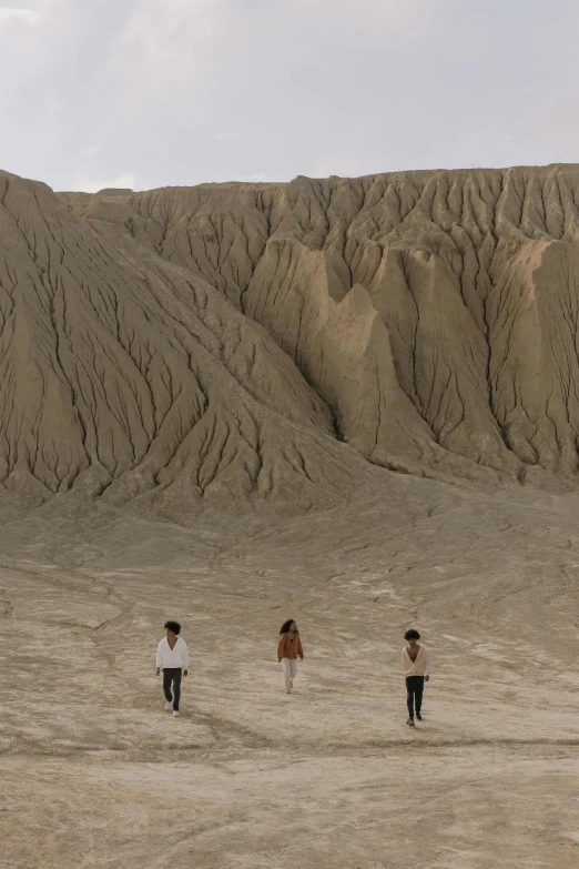 a group of people walking across a sandy field, inspired by Zhang Kechun, land art, geological strata, indonesia, huge chasm, helio oiticica