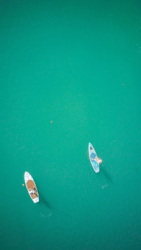 a couple of boats floating on top of a body of water, a high angle shot, sup, thumbnail, teal