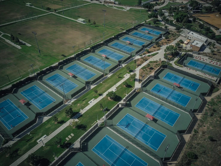 a group of tennis courts sitting on top of a lush green field, a portrait, profile image, southern california, drone photo