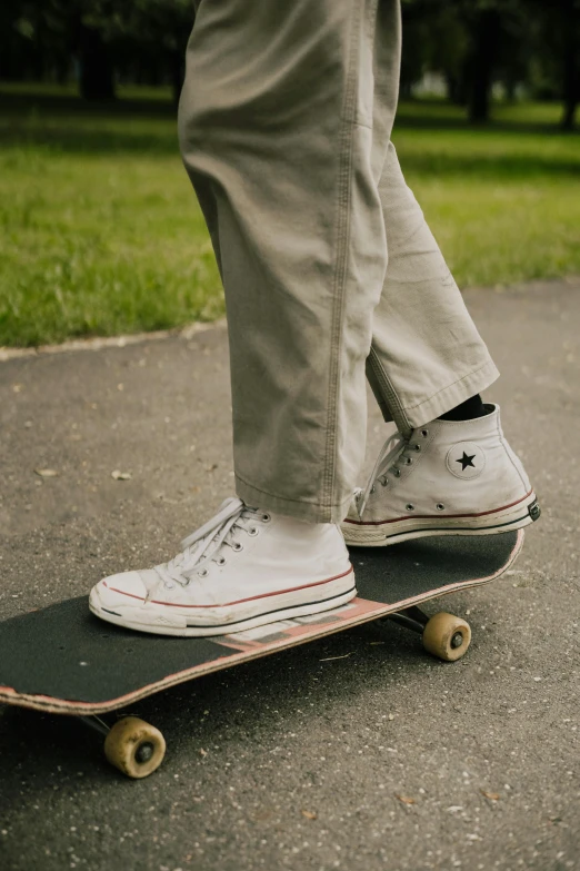 a person standing on a skateboard in a park, converse, khakis, curated collections, action sports