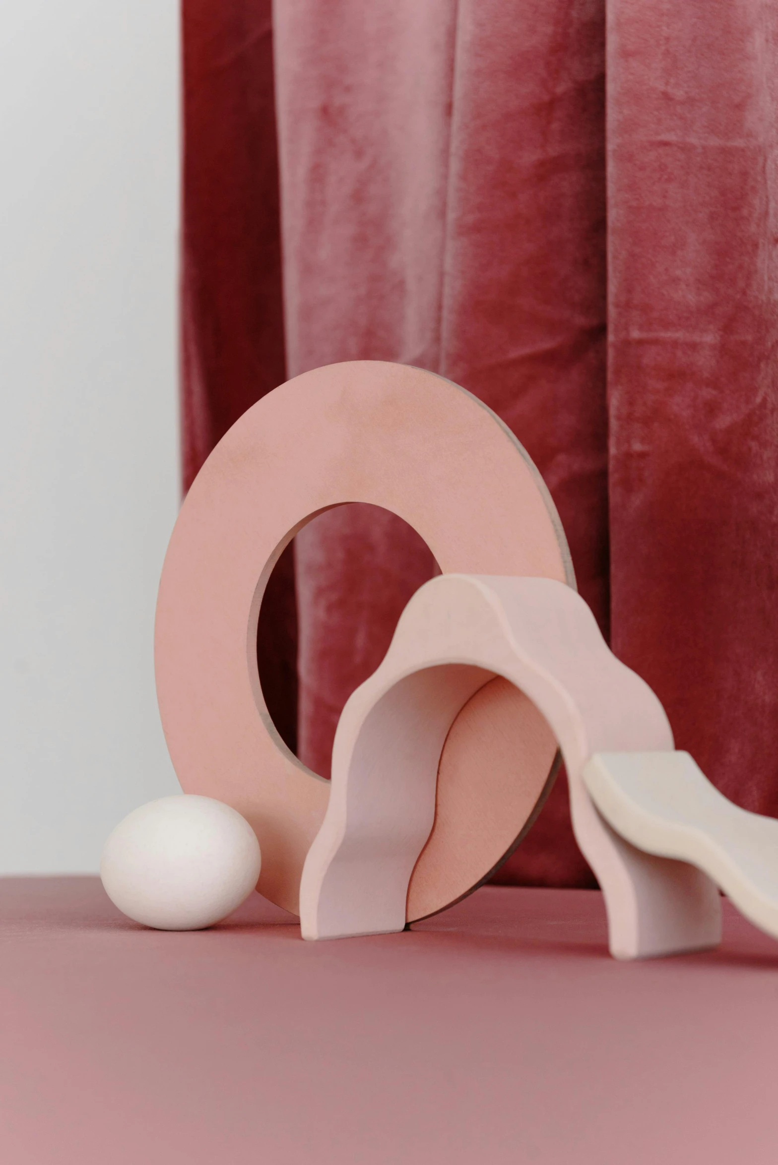 a close up of a wooden object on a table, an abstract sculpture, inspired by Isamu Noguchi, trending on unsplash, pink arches, made of silk paper, softplay, soft vignette