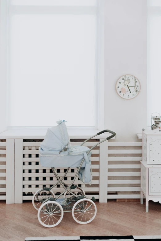 a baby carriage sitting on top of a wooden floor, poster art, by Will Ellis, pexels contest winner, fine art, white room, watch photo, white and pale blue, bedroom background
