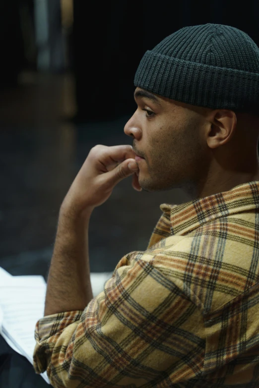 a man sitting in front of a laptop computer, a portrait, by William Berra, trending on pexels, frank ocean, sideways glance, production still, he also wears a grey beanie