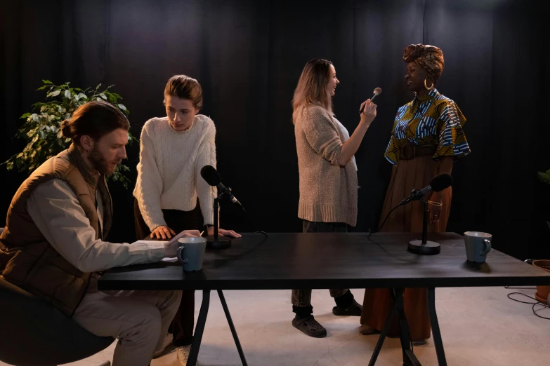 a group of people standing around a table, performance art, holding a microphone, realistic »