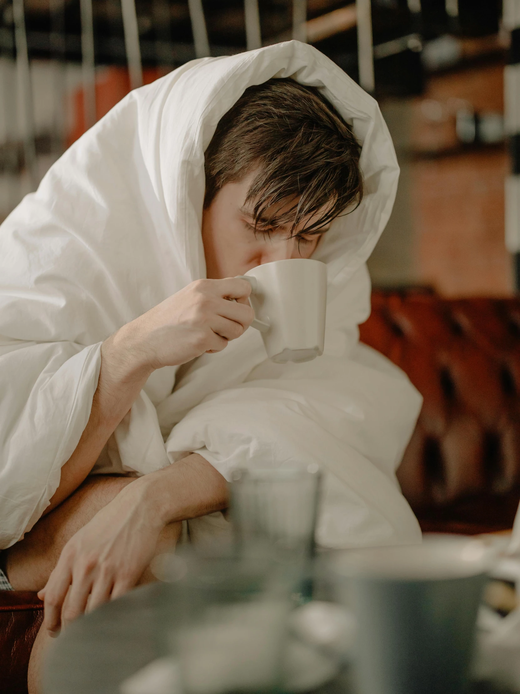 a man laying in bed with a cup of coffee, by Jan Tengnagel, pexels contest winner, cloak covering face, gif, cafe, declan mckenna