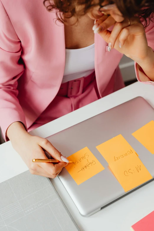 a woman sitting at a table with a laptop and sticky notes on it, trending on pexels, yellow and orange color scheme, whiteboards, pink and gold color scheme, thumbnail