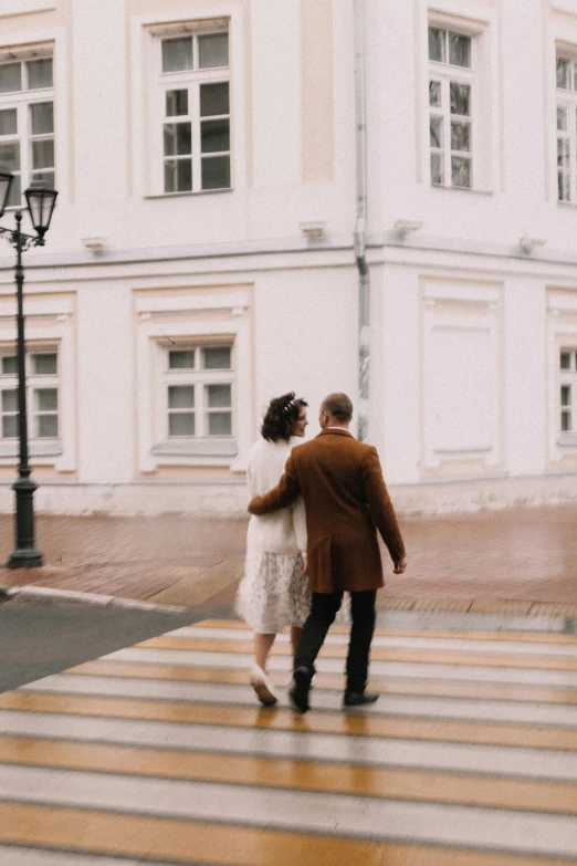 a man and a woman walking across a crosswalk, pexels contest winner, neo-romanticism, white buildings, ukrainian, vintage inspired, brown