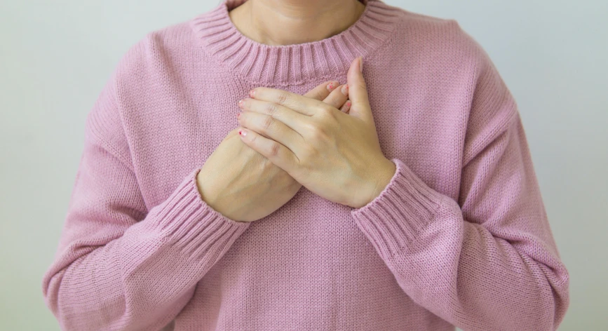 a woman in a pink sweater is holding her hands together, heart emblem on chest, quack medicine, lined in cotton, nostlagia