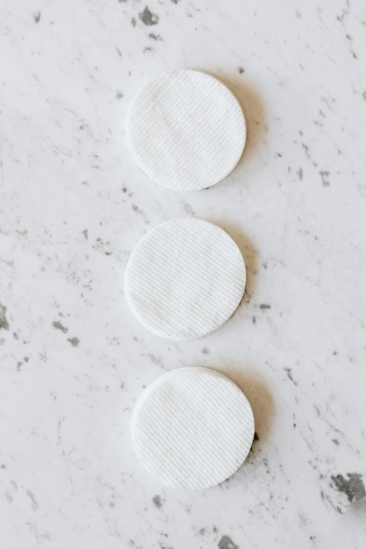 three white pads sitting on top of a counter, by Nicolette Macnamara, unsplash, porcelain organic tissue, small round face, white background, stippled