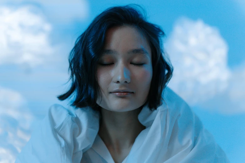 a woman in a white shirt with her eyes closed, pexels contest winner, surrealism, cold blue light, young cute wan asian face, humans sleeping in healing pods, partly cloudy