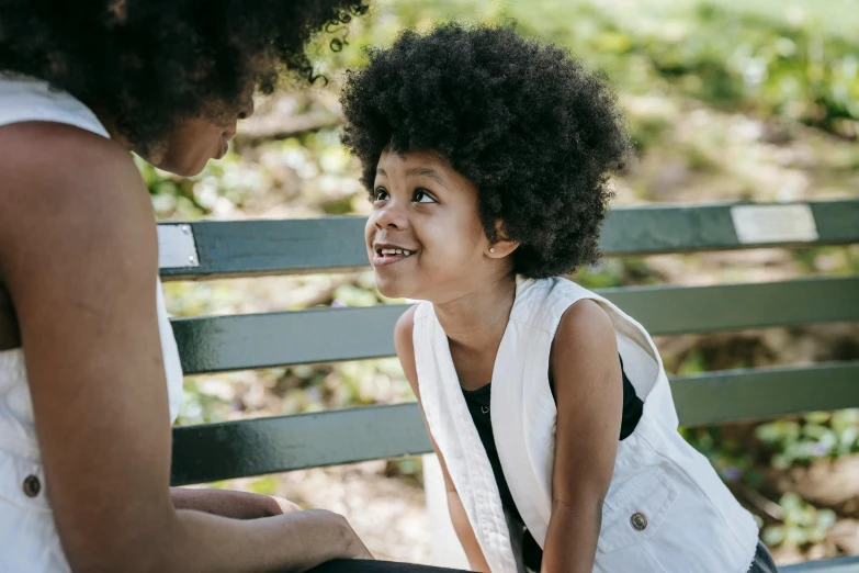 a little girl sitting on a bench next to a woman, pexels contest winner, afro hair, smiling at each other, 4yr old, black