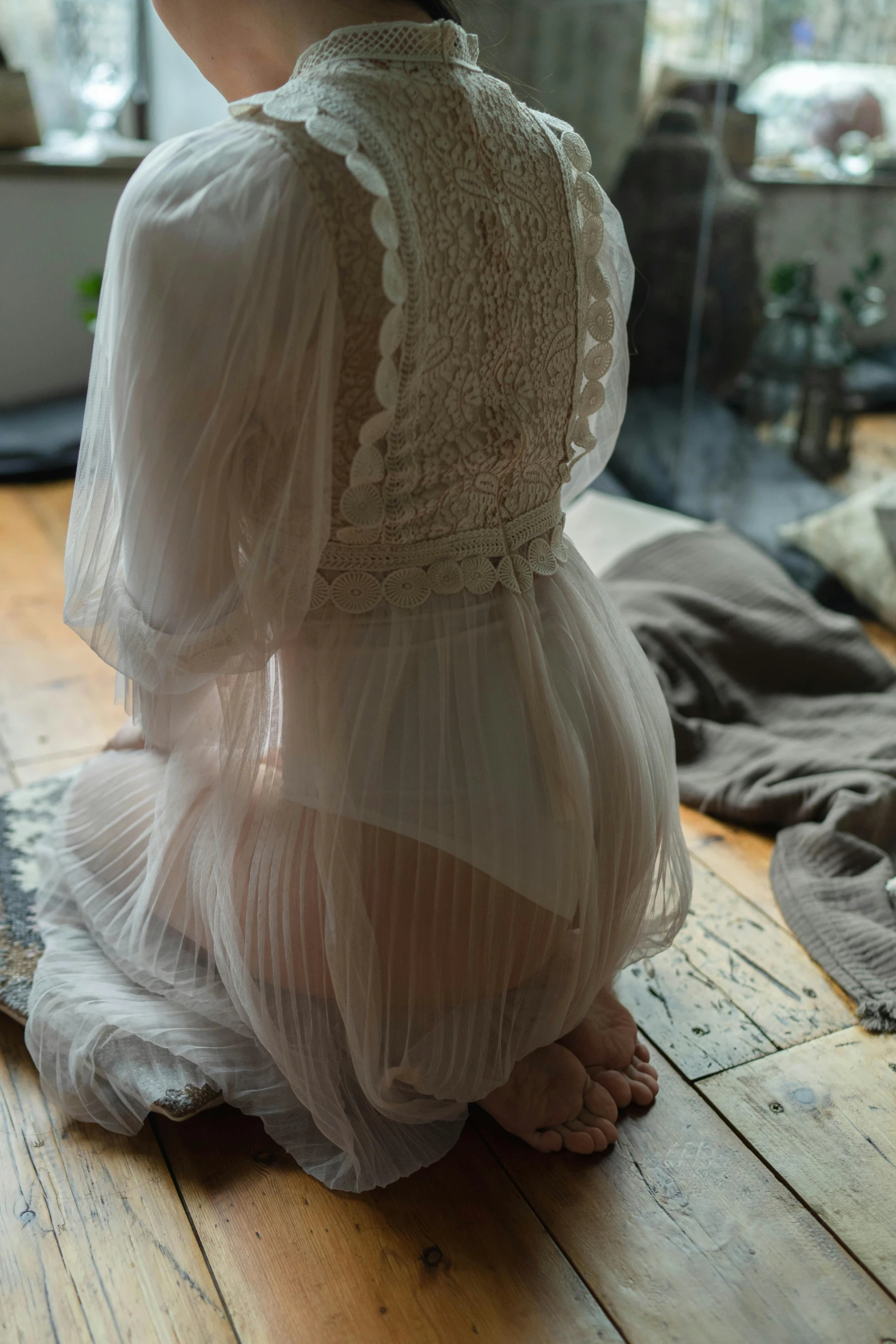 a woman in a white dress sitting on a wooden floor, inspired by Elsa Bleda, unsplash, renaissance, soft translucent fabric folds, laced lingerie, back - shot, in detail