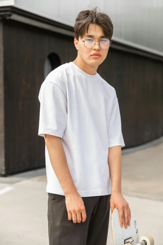 a young man holding a skateboard in front of a building, unsplash, white t-shirt, dolman, yusuke nakano, high detailed)