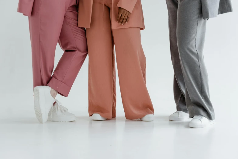 a group of three women standing next to each other, trending on pexels, baggy pants, in muted colours, clean lines, pinks