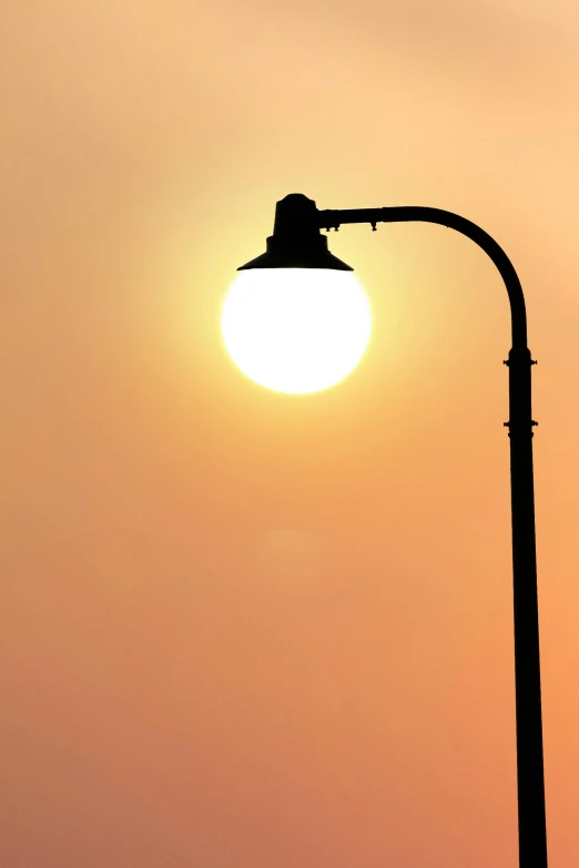 a street light with the sun setting in the background, by Ian Fairweather, floor lamps, artificial light, trending on, bright sky