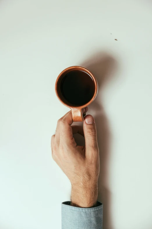 a man's hand holding a cup of coffee, by James Morris, trending on unsplash, minimalism, made of glazed, medium poly, top, long