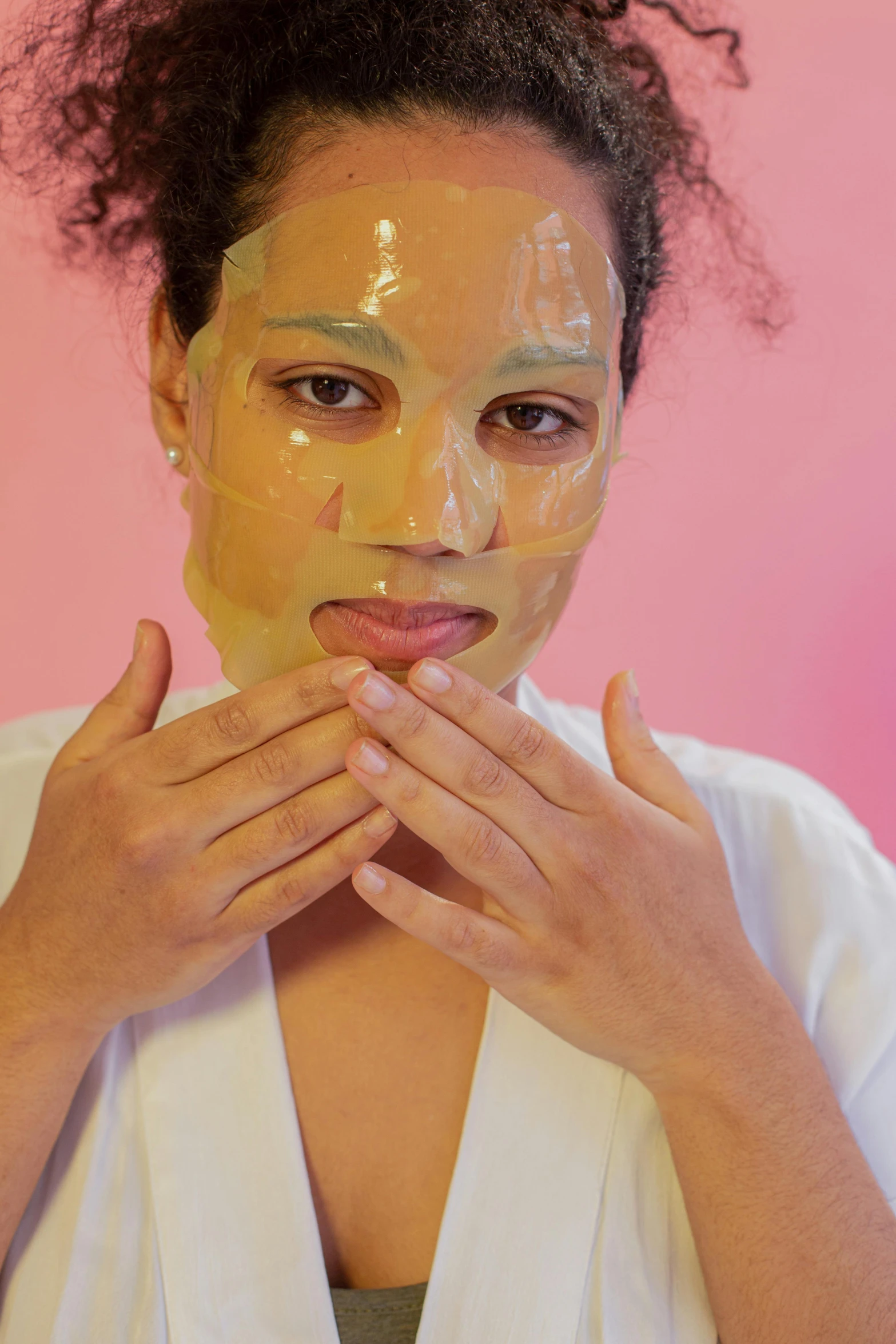 a woman with a facial mask covering her face, on a yellow paper, light-brown skin, on clear background, pink face