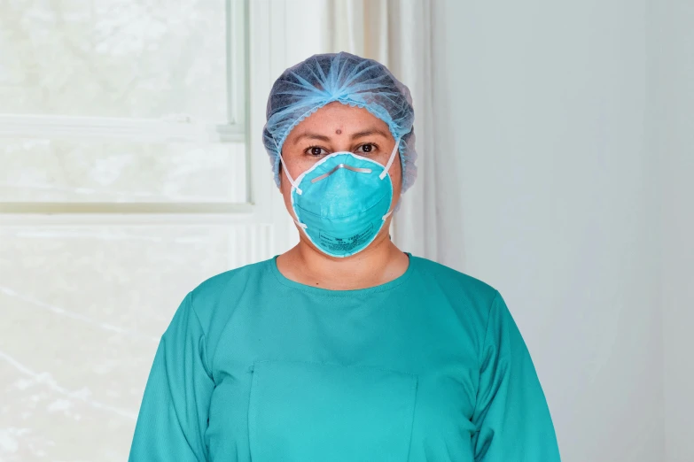 a woman wearing a surgical mask standing in front of a window, hurufiyya, teal uniform, sterile background, portrait n - 9, round-cropped