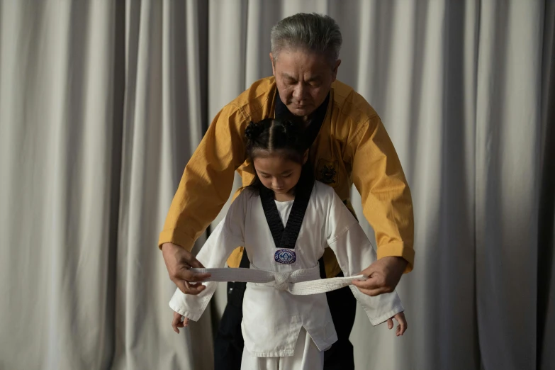 a woman standing next to a little girl who is cutting a piece of paper, inspired by Kanō Shōsenin, pexels contest winner, white belt, father figure image, wearing long silver robes, jeongseok lee