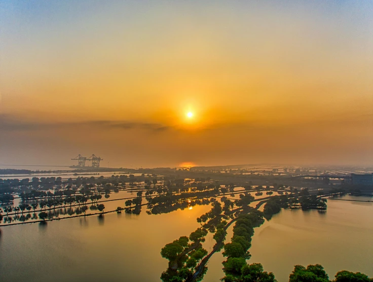 the sun is setting over a large body of water, by Jan Tengnagel, pexels contest winner, industrial fires and smog, river delta, hoang lap, panorama view