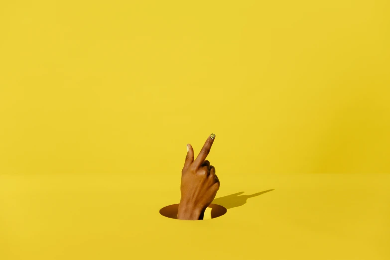 a hand with two fingers sticking out of a hole, by Matthias Stom, trending on pexels, postminimalism, yellow magic theme, 3d minimalistic, high quality product image”, dunce
