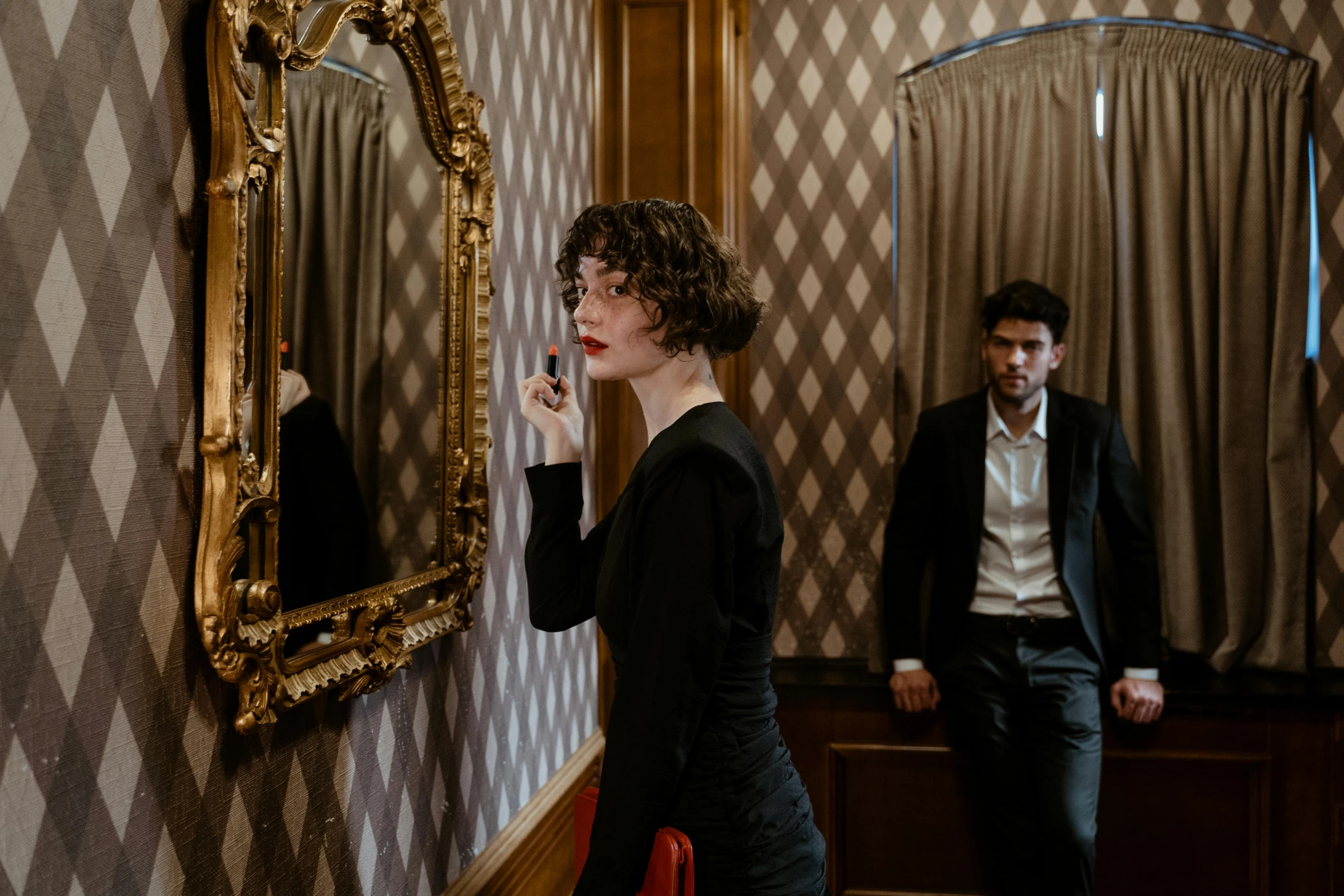 a woman in a black dress standing in front of a mirror, by Emma Andijewska, pexels contest winner, serial art, finn wolfhard, an elegant couple, still from a wes anderson film, a handsome