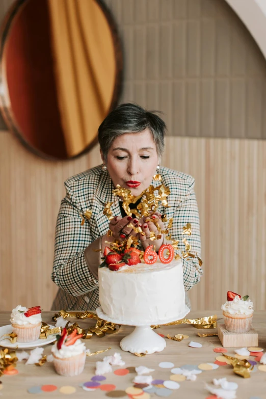 a woman blowing out candles on a cake, by Julia Pishtar, silver gold red details, caramel, entertaining, bakery