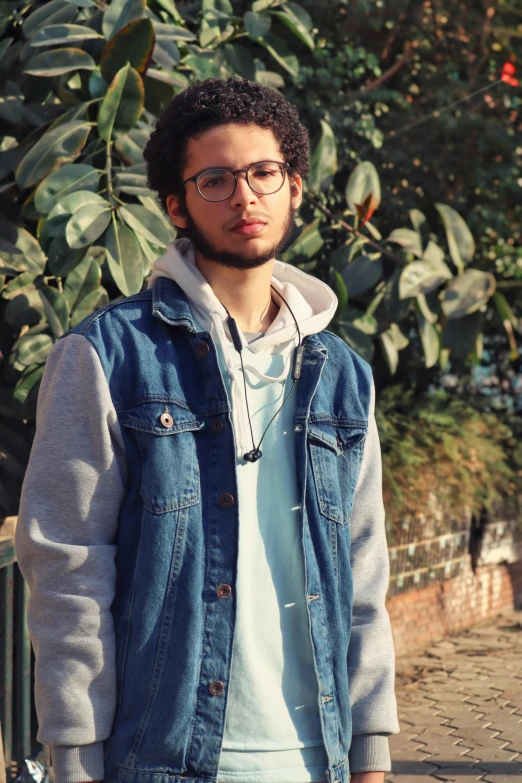 a man standing on a sidewalk with a skateboard, an album cover, by Ahmed Yacoubi, renaissance, wearing a jeans jackets, headshot profile picture, trees in the background, ((portrait))