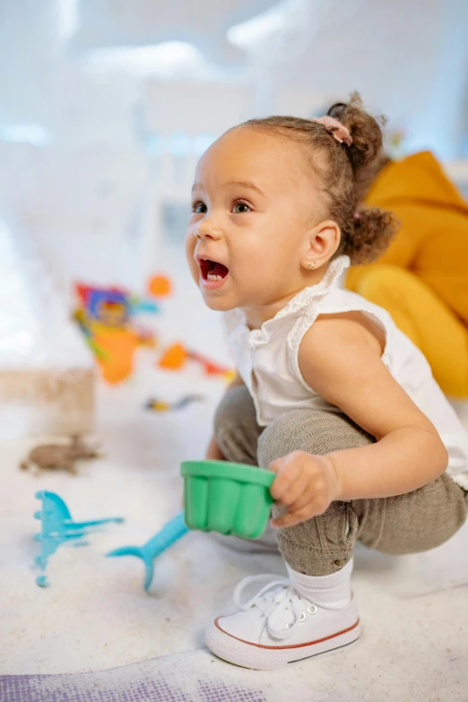 a baby sitting on the floor playing with toys, pexels contest winner, covered in white flour, she is smiling and excited, screensaver, actress