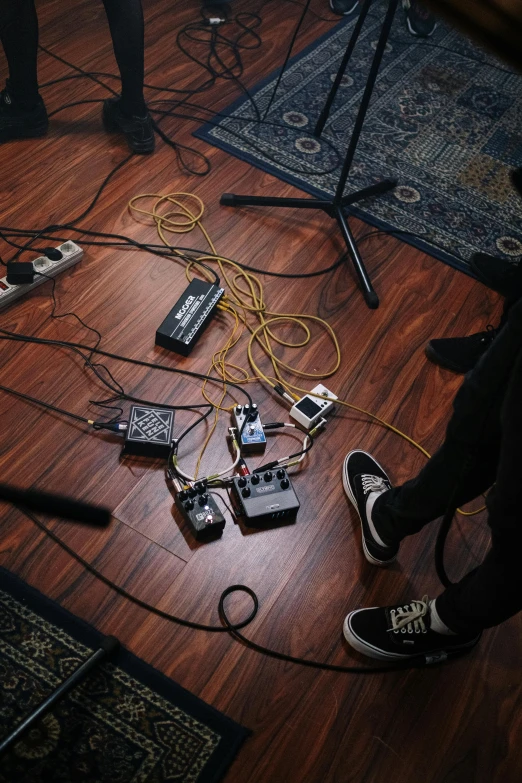 a group of people standing on top of a hard wood floor, an album cover, by Robbie Trevino, reddit, cables on floor, practice, epk, performing