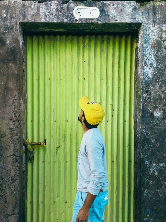 a man standing in front of a green door, a picture, pexels contest winner, happening, yellow cap, assamese aesthetic, ( colorful ), lime green