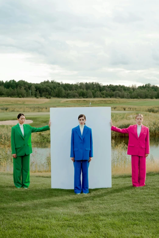 a group of people standing on top of a lush green field, an album cover, by Marina Abramović, color field, three piece suit, finland, blue and pink shift, wearing a colorful men's suit