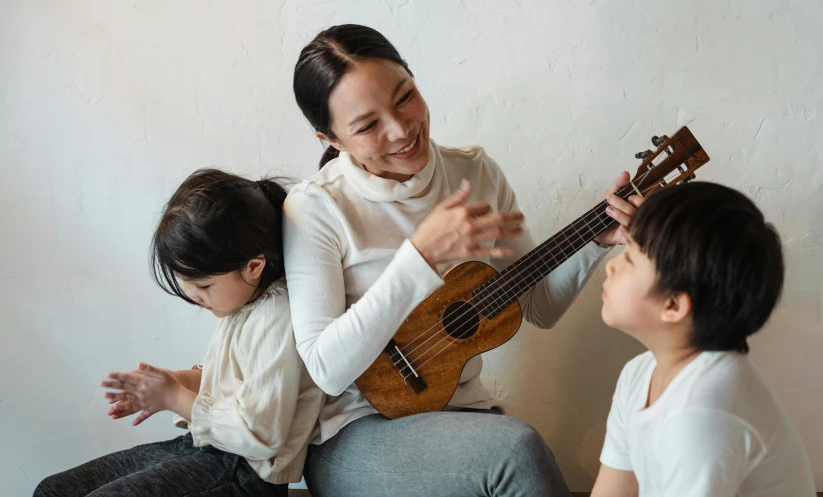 a woman playing a guitar with two children, pexels contest winner, shin hanga, holding an epée, manuka, thumbnail, teacher