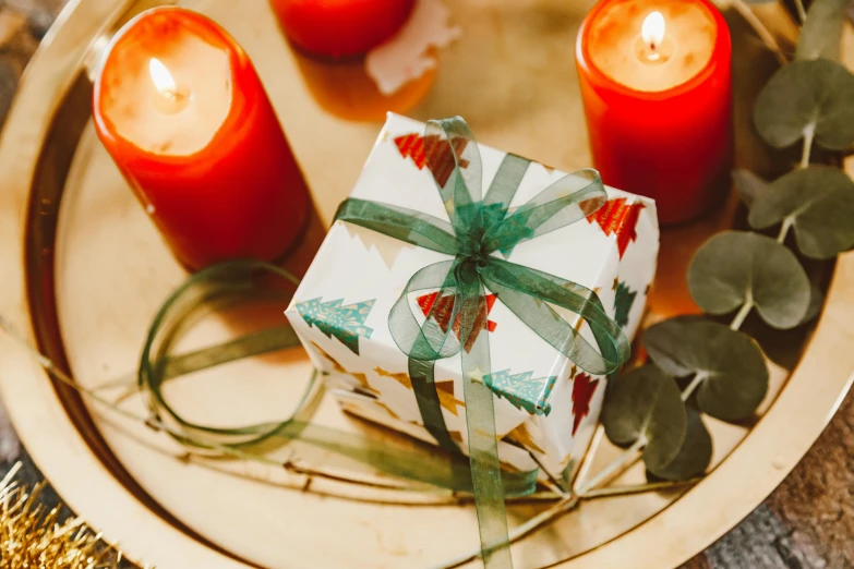 a close up of a present on a plate with candles, by Emma Andijewska, pexels contest winner, arts and crafts movement, square, olive green and venetian red, high quality paper, a wooden