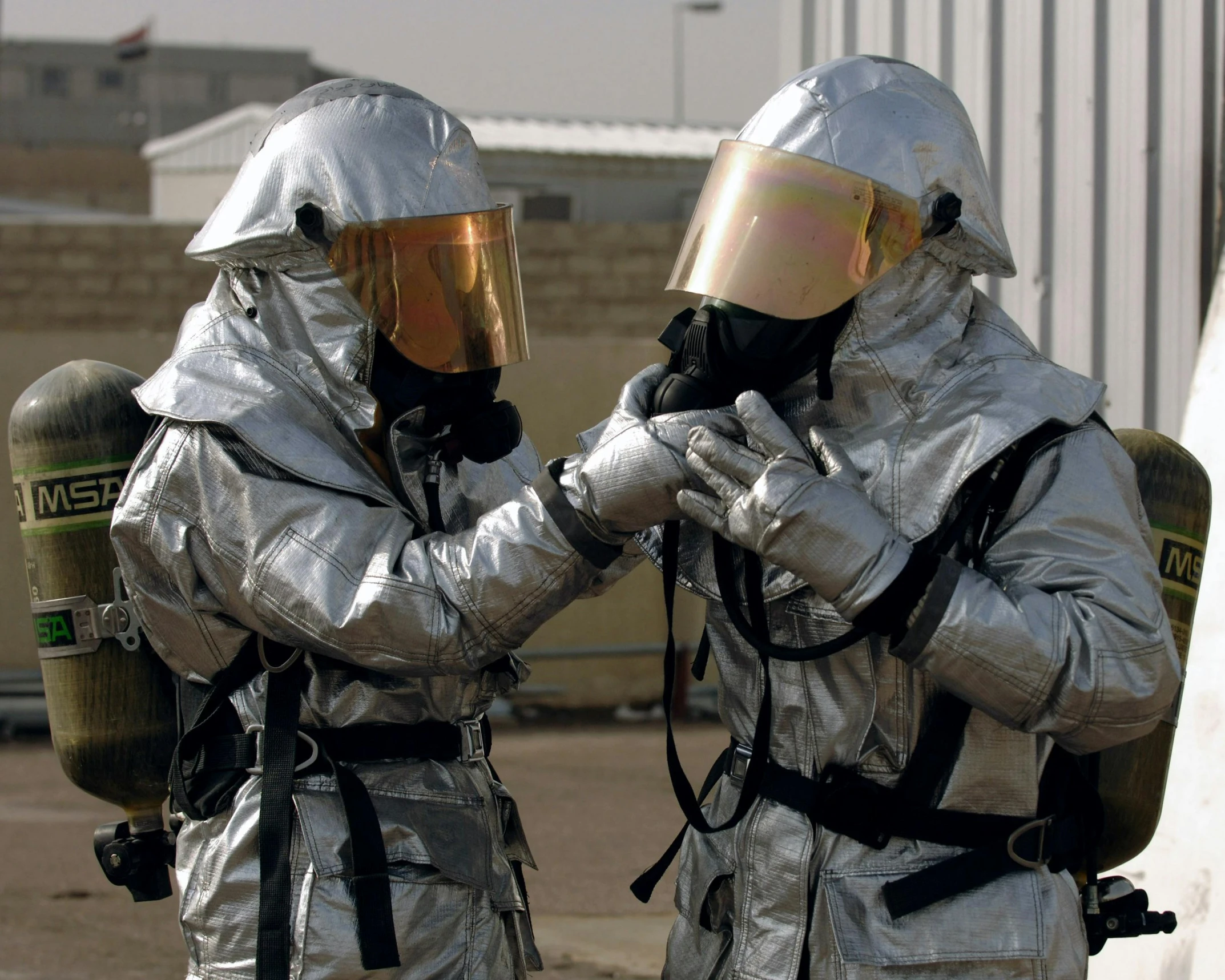 a couple of men in silver suits standing next to each other, a photo, pixabay, happening, firefighting gear, biohazard, military, brown