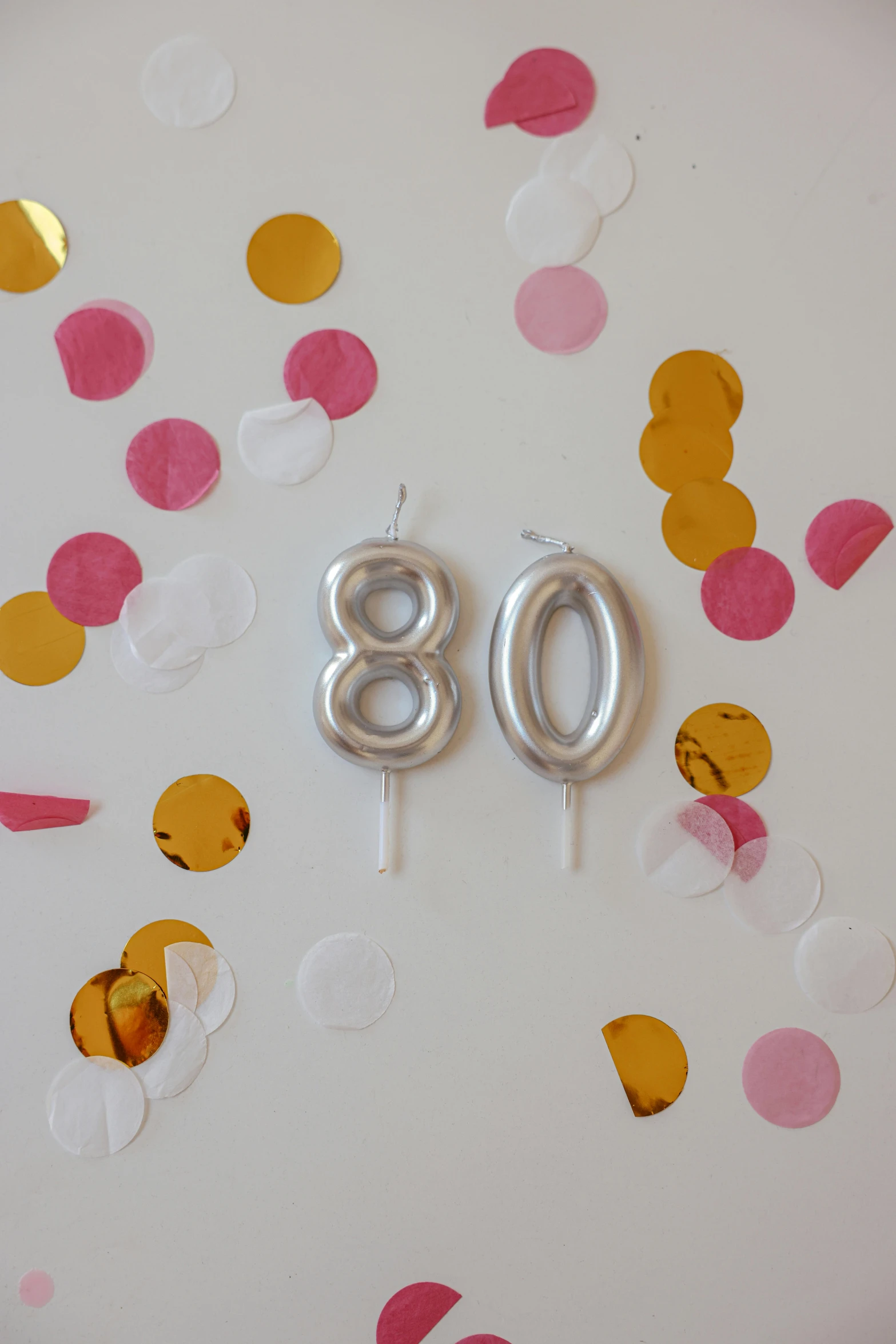 a white plate topped with silver balloons and confetti, a cartoon, shutter speed is 8 0, waxy candles, | 28mm |, golden number