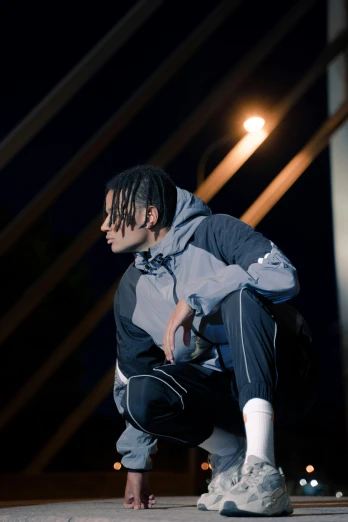 a man kneeling on the ground with a skateboard, an album cover, unsplash, realism, xxxtentacion, reflective suit, profile image, performing on stage