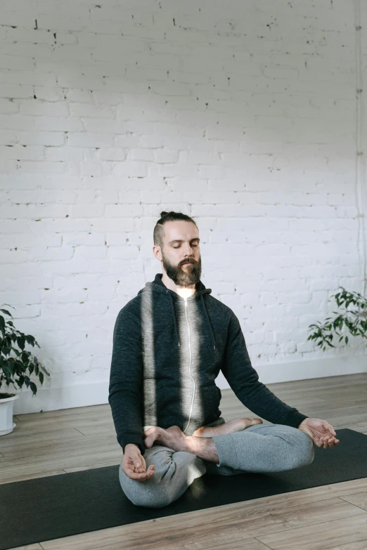 a man sitting on top of a yoga mat, a hologram, by Adam Marczyński, trending on pexels, light beard, low quality photo, breathing, centered in image