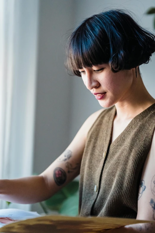 a woman sitting at a table with a plate of food, a tattoo, trending on unsplash, process art, bowl haircut, star trek asian woman, studying in a brightly lit room, photograph of a sleeve tattoo