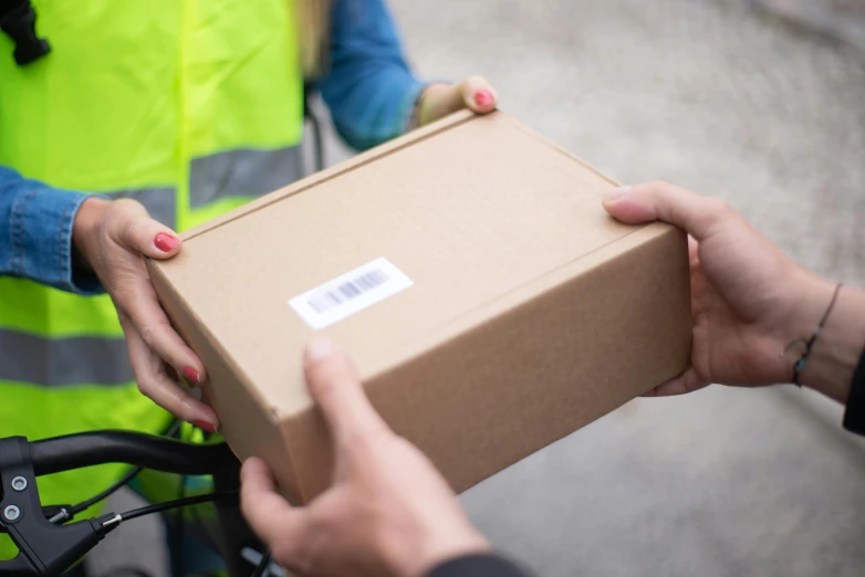 a person handing a box to another person on a bike, wearing hi vis clothing, middle close up, etsy, avatar image