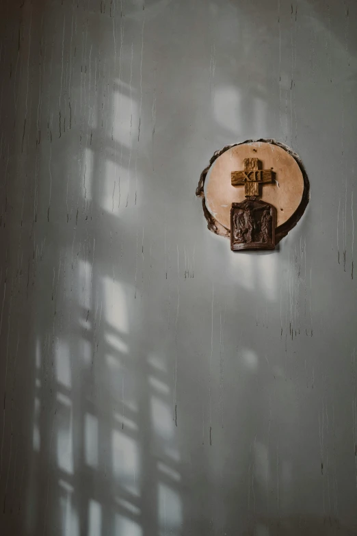 a clock mounted to the side of a wall, unsplash, light and space, shadow of catholic church cross, orthodox icon, worn, 15081959 21121991 01012000 4k