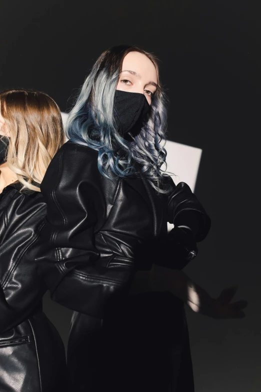 a couple of women standing next to each other, an album cover, inspired by Elsa Bleda, trending on pexels, realism, techwear, gradient black to silver, leather, face covered