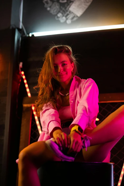 a woman sitting on a stool in front of a neon sign, trending on pexels, sydney sweeney, nightclub dancing inspired, smiling down from above, ( ( theatrical ) )