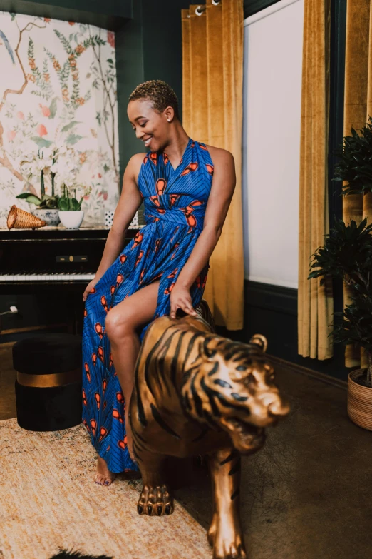 a woman in a blue dress sitting on a tiger statue, by Carey Morris, maximalism, standing in corner of room, ( ( dark skin ) ), tyler, wearing a cocktail dress